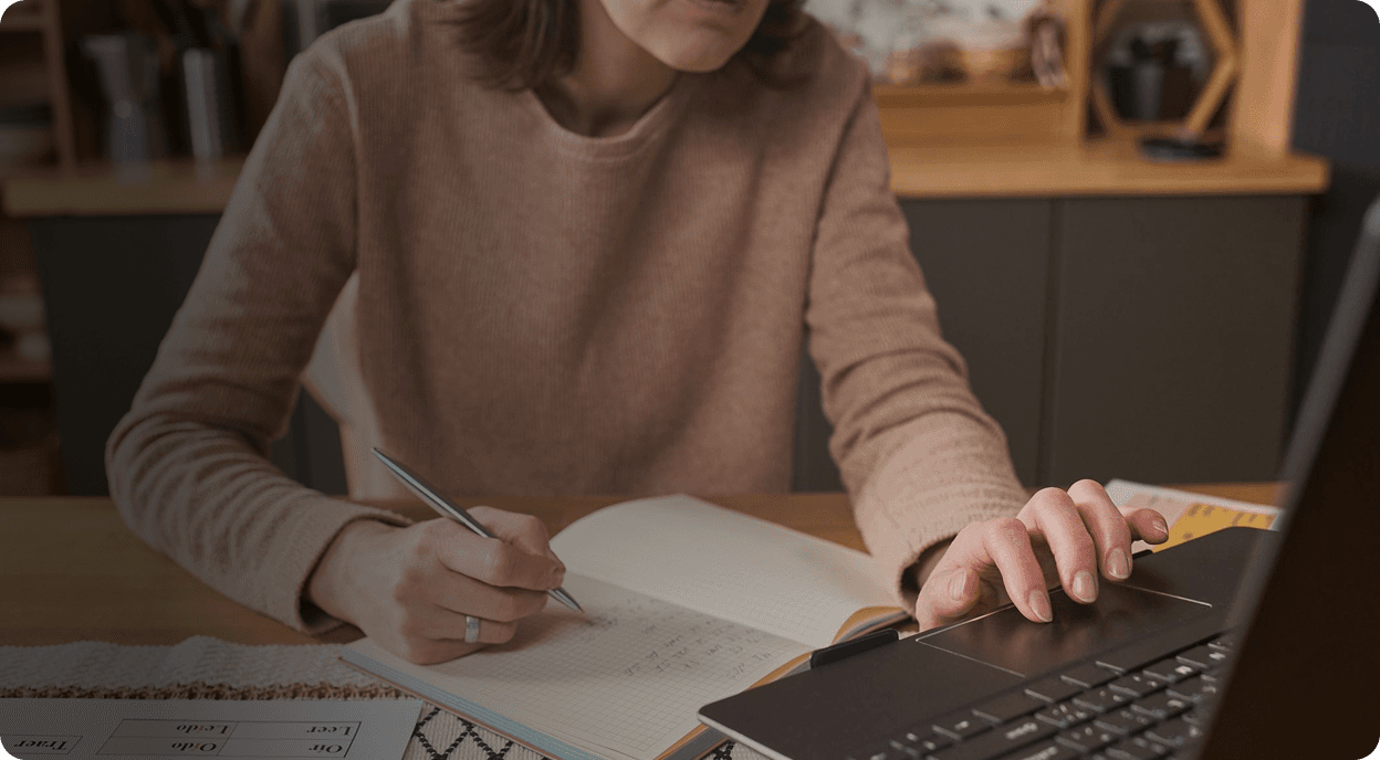 Student taking notes while studying online